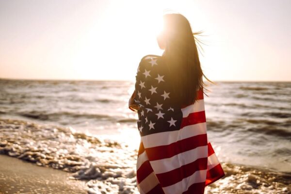 woman with american flag on beach