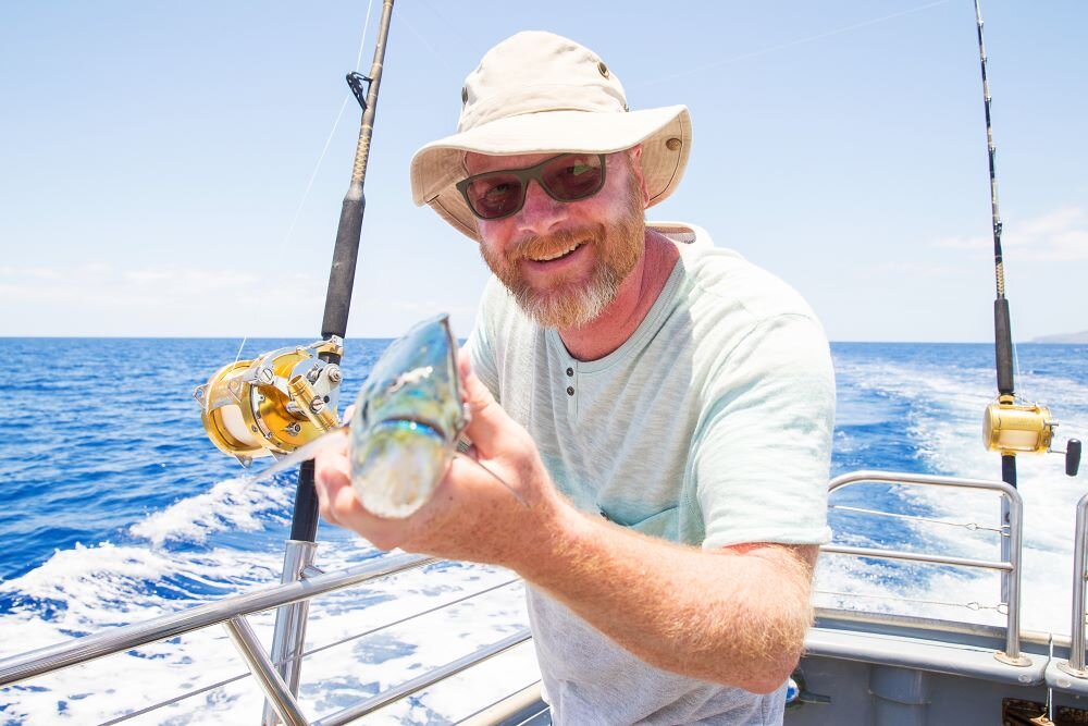 man holding fish on a boat