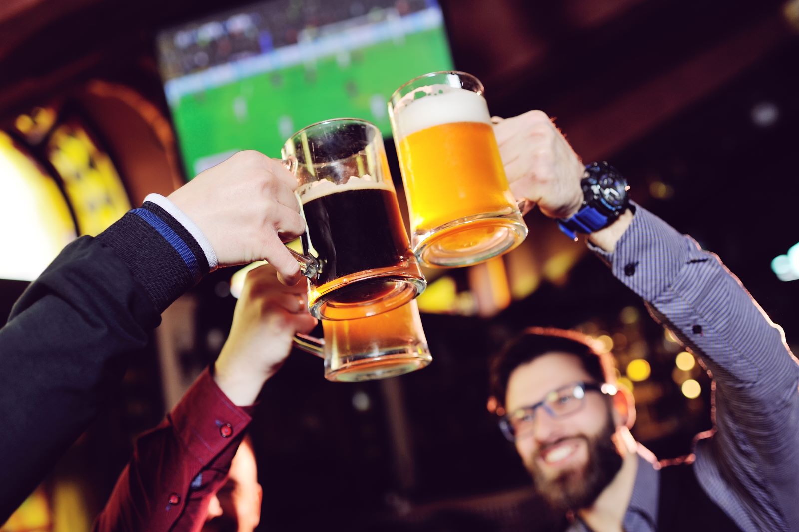 group of friends drinking in front of TV at sports bar